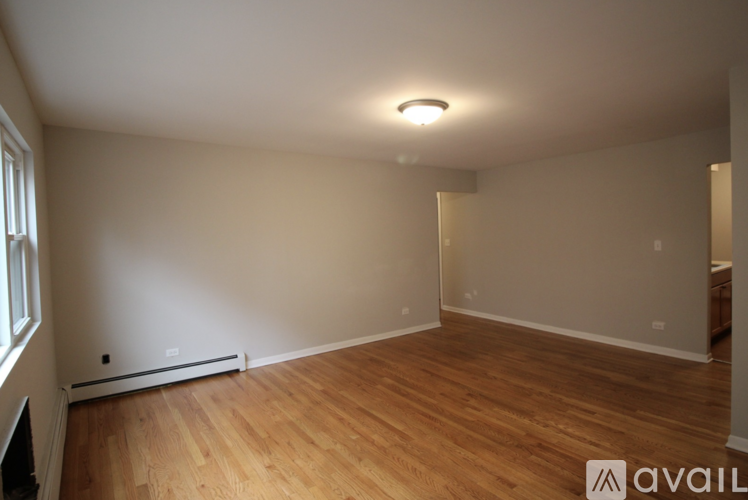 A room with wooden flooring and a window on the left side.