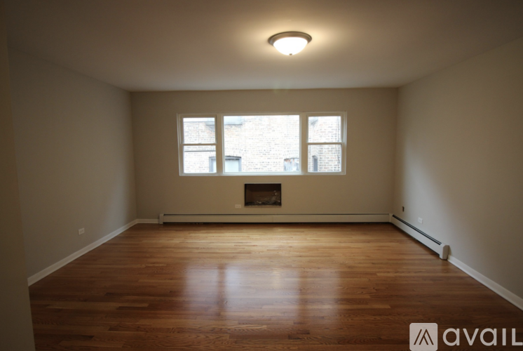 A room with wooden floors and a fireplace with a window above it.