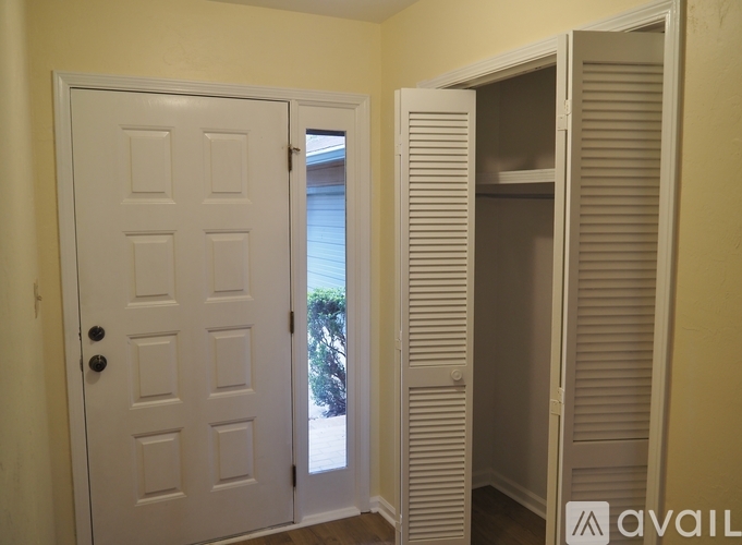 A white door with a black handle is open to a room with a white closet.