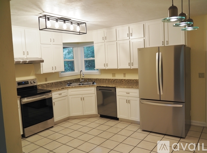 A kitchen with white cabinets and a stainless steel refrigerator.