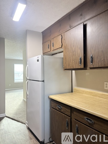 A white refrigerator in a kitchen with wooden cabinets.