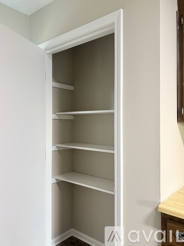 A white open pantry with empty shelves.