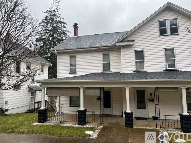 A white house with a grey roof and a black gate.