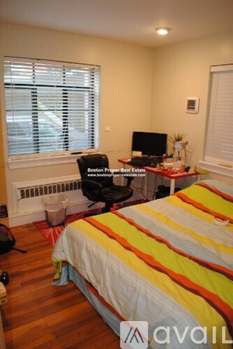 A bedroom with a bed, desk, and window.