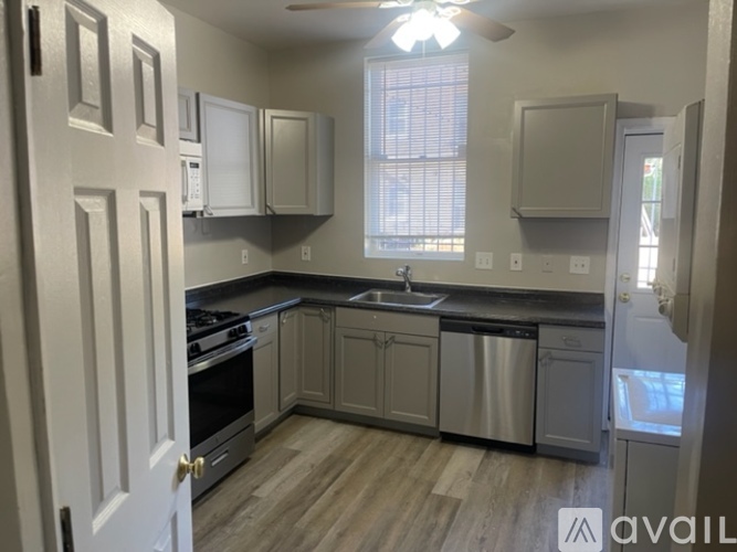 A kitchen with a stove, sink, and cabinets.