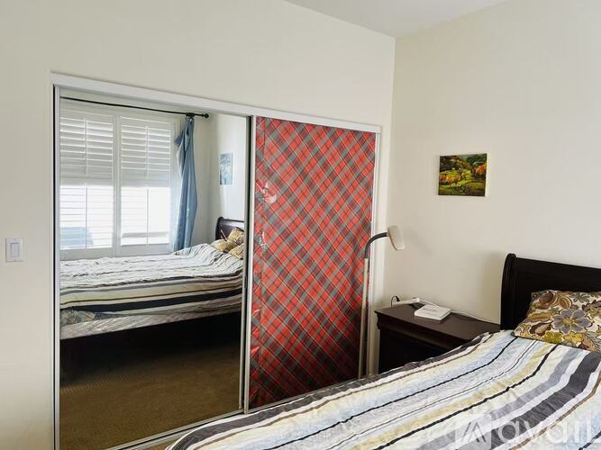 A bedroom with a bed, a mirror, and a window.