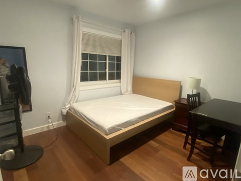 A bedroom with a bed, desk, and chair.