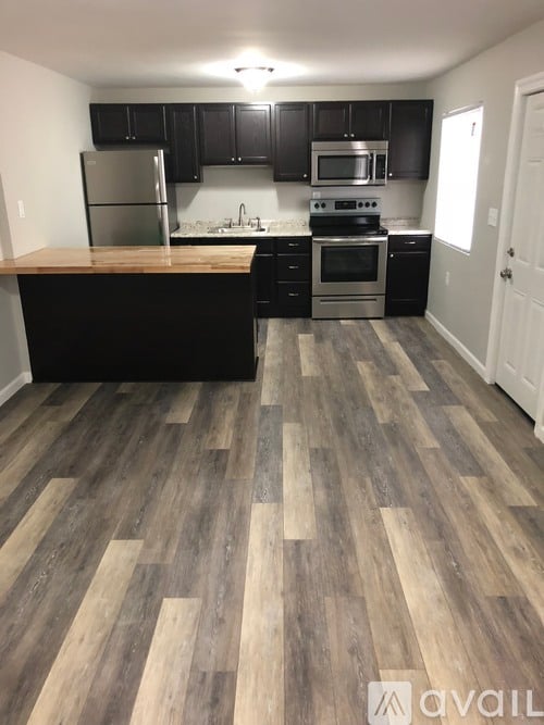 A kitchen with black cabinets and a wooden floor.