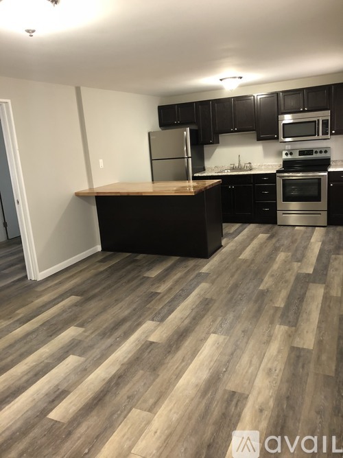 A kitchen with a wooden floor and stainless steel appliances.