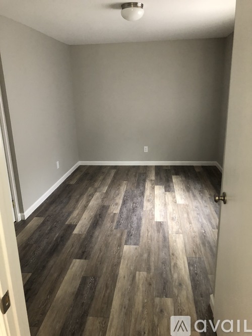 A room with wooden flooring and a door on the left.