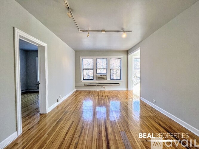 A spacious room with wooden floors and a large window.