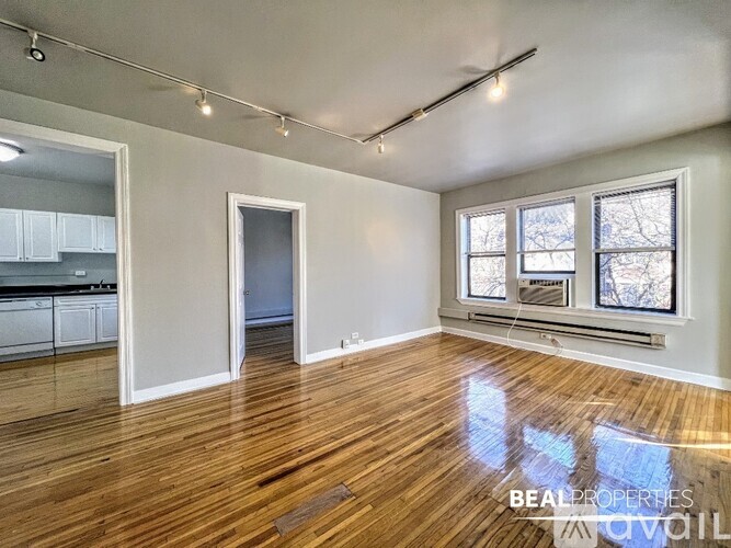 A spacious room with wooden floors and a large window.