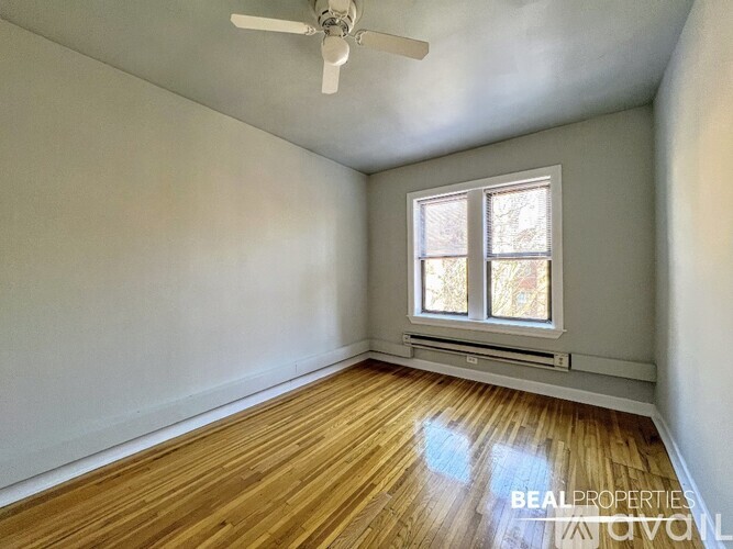 A room with a ceiling fan and a window with a view of trees.