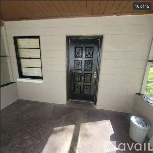 A black door with a window to the left and a trash can to the right.