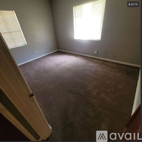 A room with a carpeted floor and a window with blinds.