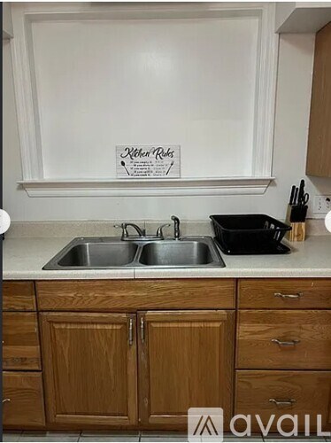 A kitchen with a sink and a sign that says "Kitchen Rules".