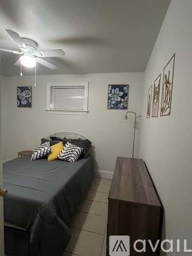 A bedroom with a bed, a ceiling fan, and a wooden table.