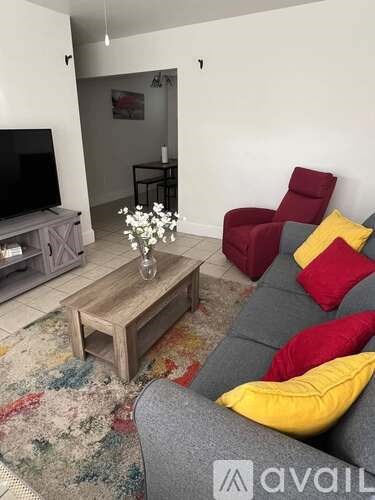 A living room with a grey couch, a wooden coffee table, and a television.