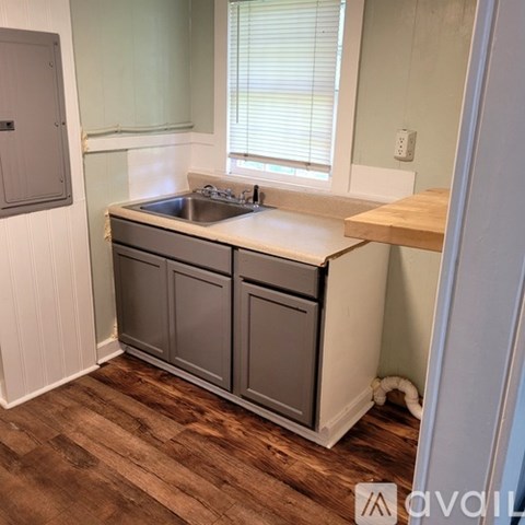 A kitchen with a sink, cabinets and a wooden floor.