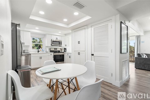 A modern kitchen with white cabinets and a dining table with four chairs.