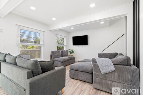 A living room with grey couches and a flat screen TV mounted on the wall.