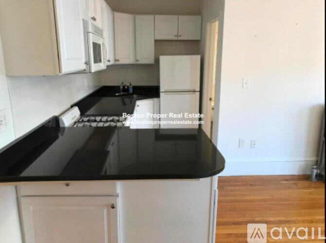 A kitchen with black countertops and white cabinets.