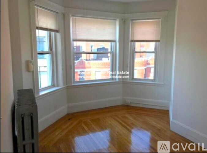 A room with a radiator and wooden floors is available for rent.