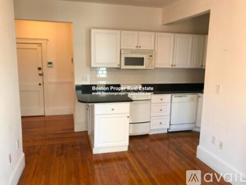 A kitchen with white cabinets and a black countertop.
