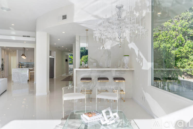 A modern living room with white furniture and a glass table.