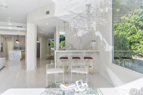 A modern living room with white furniture and a glass table.