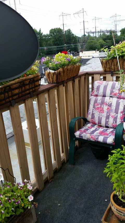 A wooden balcony with a chair and potted plants.