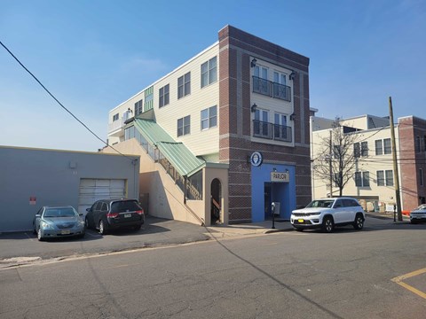 A building with a blue sign on the front and cars parked in front.