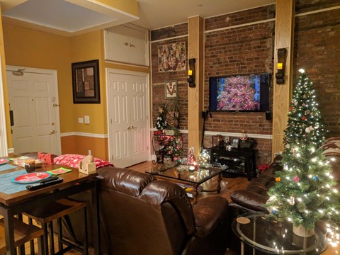 A living room with a brown leather couch and a Christmas tree.