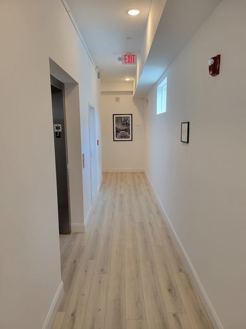 A long hallway with wood floors and white walls.