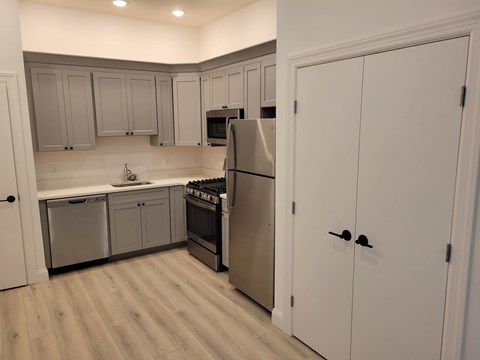 A kitchen with a refrigerator, oven, and sink.