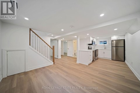 A spacious, well-lit kitchen area with wooden flooring and white cabinetry.