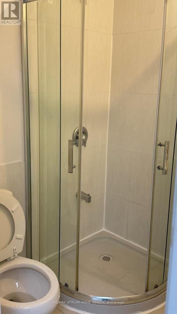 A white toilet sits next to a glass shower door.