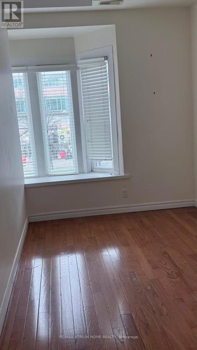 A room with wooden flooring and a window with blinds.
