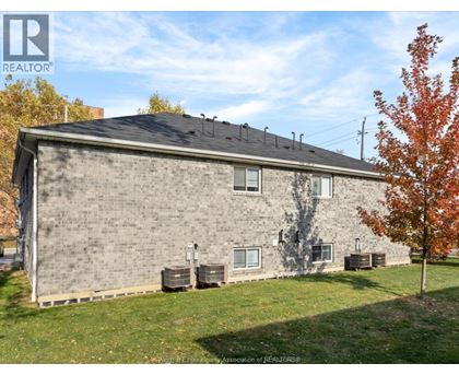 A house with a grey brick exterior and a black roof with a chimney.
