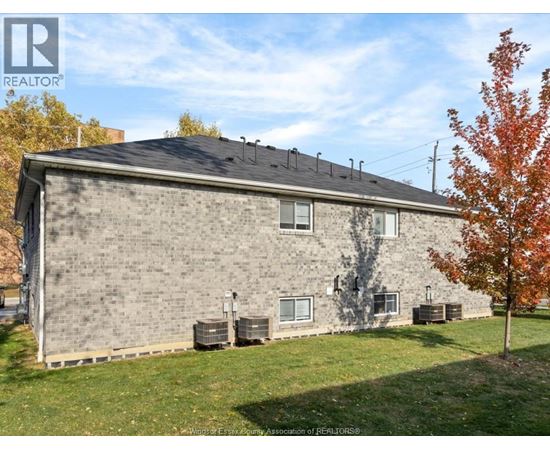A house with a grey brick exterior and a black roof with a chimney.