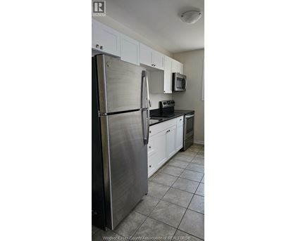 A kitchen with white cabinets and a stainless steel refrigerator.