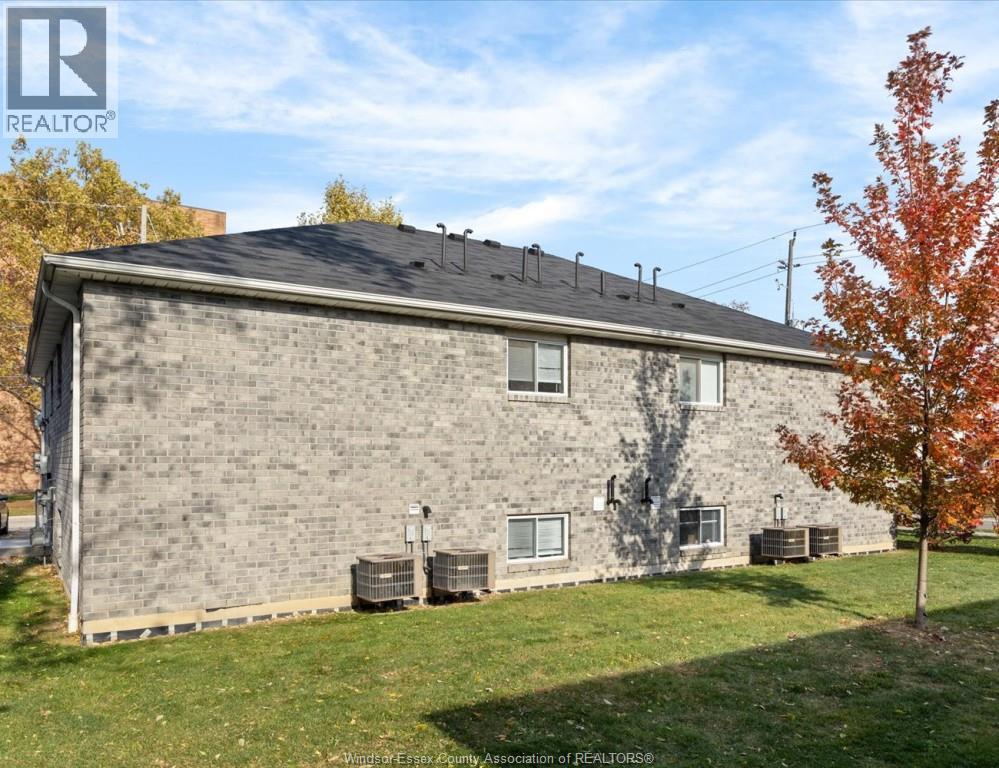 A house with a grey brick exterior and a black roof with a chimney.
