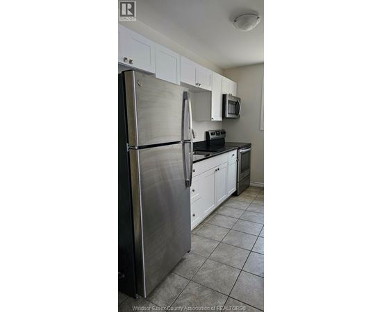 A kitchen with white cabinets and a stainless steel refrigerator.