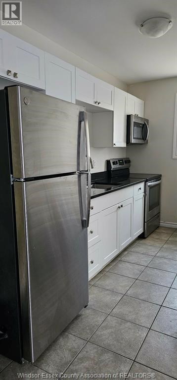 A kitchen with white cabinets and a stainless steel refrigerator.