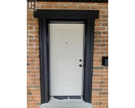 A white door with a black frame is set in a brick wall.