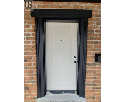 A white door with a black frame is set in a brick wall.