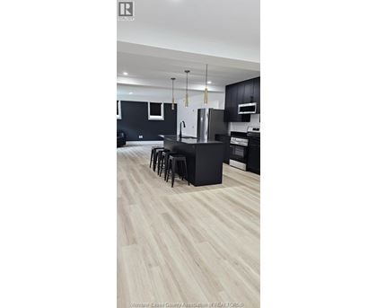 A kitchen with black cabinets and a white refrigerator.