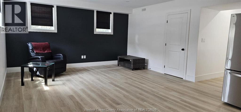 A black and white living room with a black leather chair and a wooden floor.