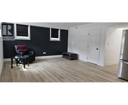 A black and white living room with a black leather chair and a wooden floor.