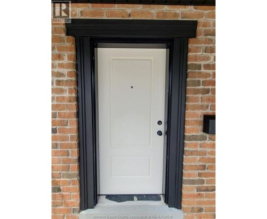 A white door with a black frame is set in a brick wall.